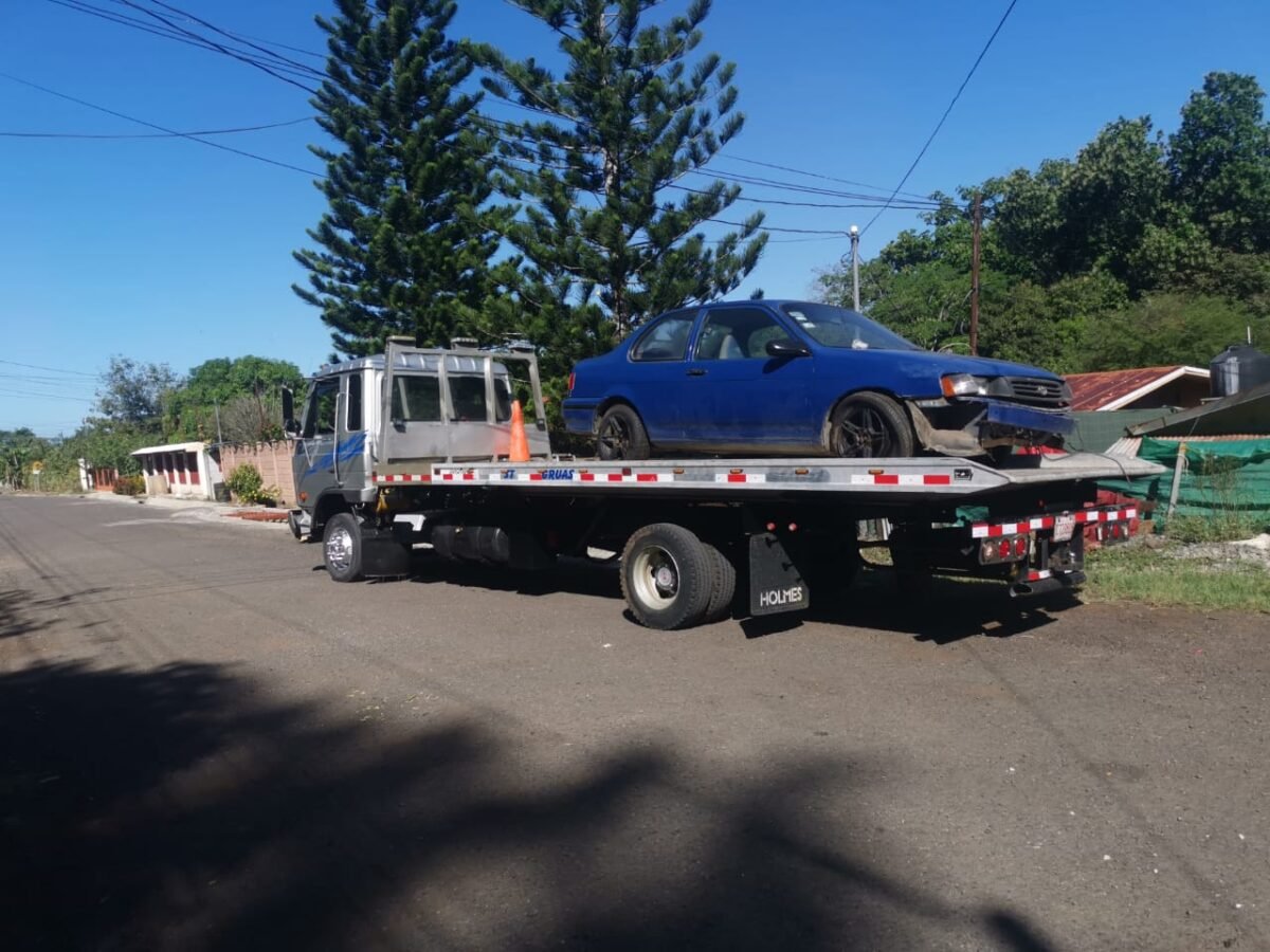 Traslado de automóvil azul en grúa plataforma
